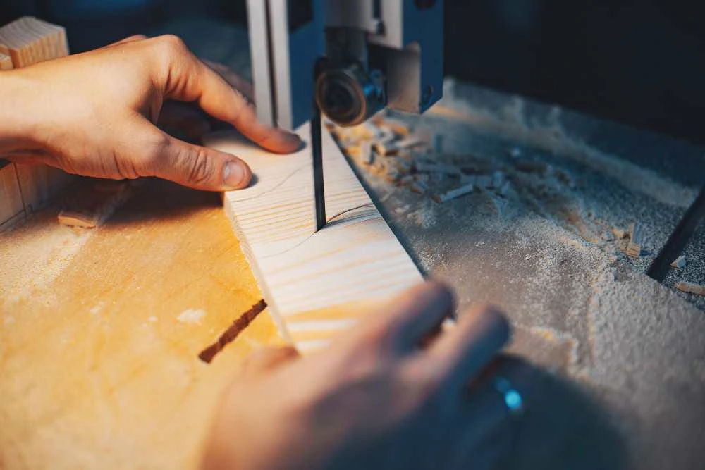 Craftsman cutting a wooden sign panel on a band saw in a sign making workshop